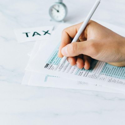 pexels photo 6863336 6863336 Hand completing tax forms with a pen, symbolizing financial deadline and time urgency.