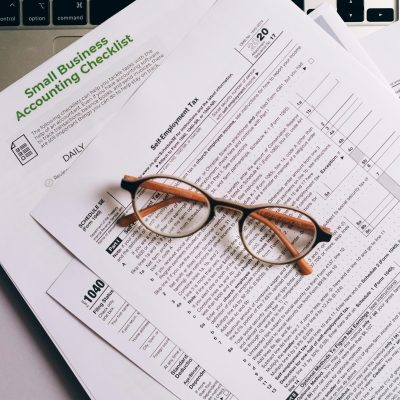 pexels photo 8962456 8962456 Overhead view of tax documents and eyeglasses on a laptop keyboard, ideal for finance or accounting themes.